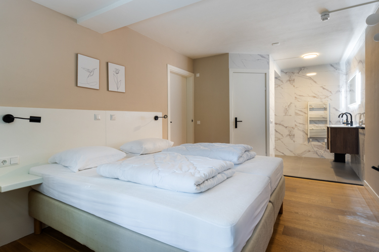 Slaapkamer met tweepersoonsbed en aangrenzende badkamer in vakantiehuis Boszicht 16a Schiermonnikoog